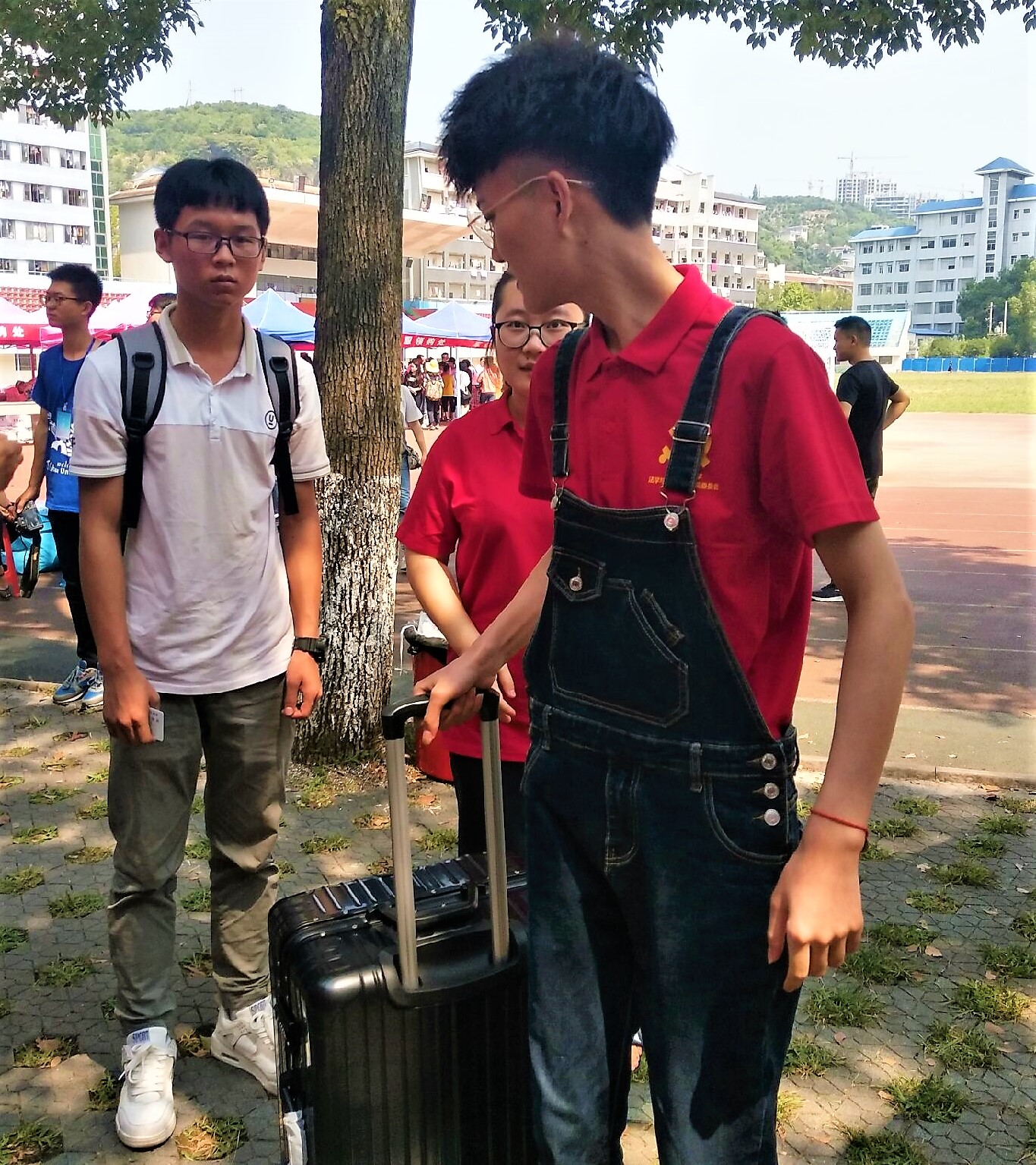 (图为 党员帮助新生拿行李并引领报到)